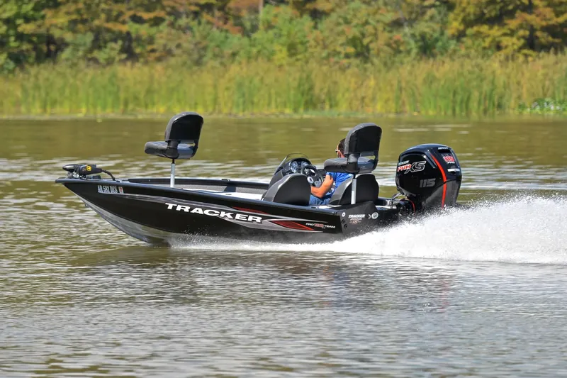 Slide: The Image of 2023 Bass Tracker PRO TEAM 190 boat speeding on a lake with lush greenery. - 4