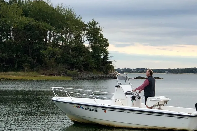 Slide: The Image of Man steering 2005 Boston Whaler 190 Nantucket boat near lush shoreline. - 17