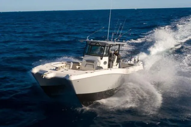 Slide: The Image of 2026 World Cat 325 CC boat on calm water under a partly cloudy sky. - 1