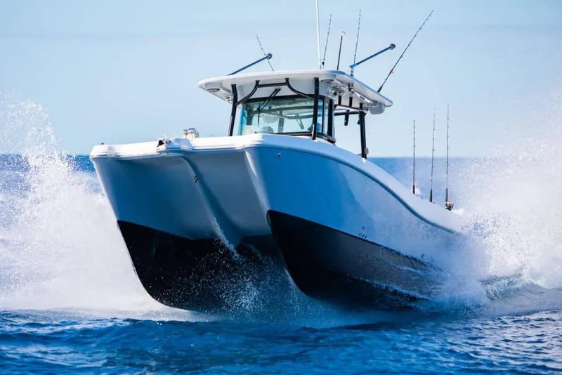 Slide: The Image of 2026 World Cat 325 CC boat on calm water under a partly cloudy sky. - 2