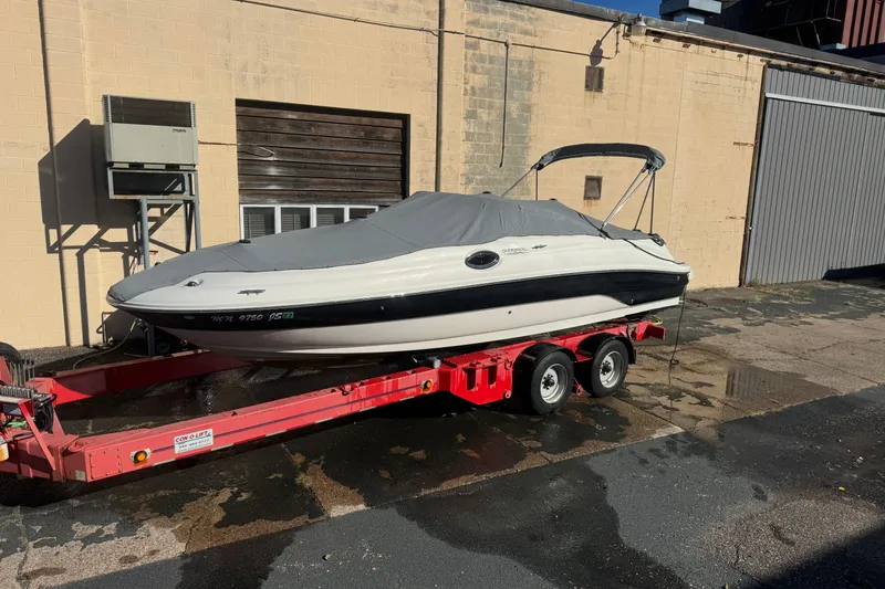 The Image of 2005 Sea Ray 240 Sundeck boat on red trailer, covered and parked outdoors. - 0