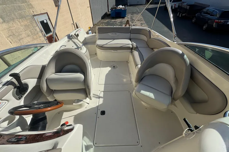 Slide: The Image of 2005 Sea Ray 240 Sundeck interior with seating and steering wheel, docked outdoors. - 10