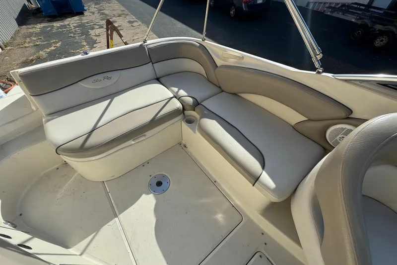 Slide: The Image of 2005 Sea Ray 240 Sundeck interior with beige seating and cup holders. - 13