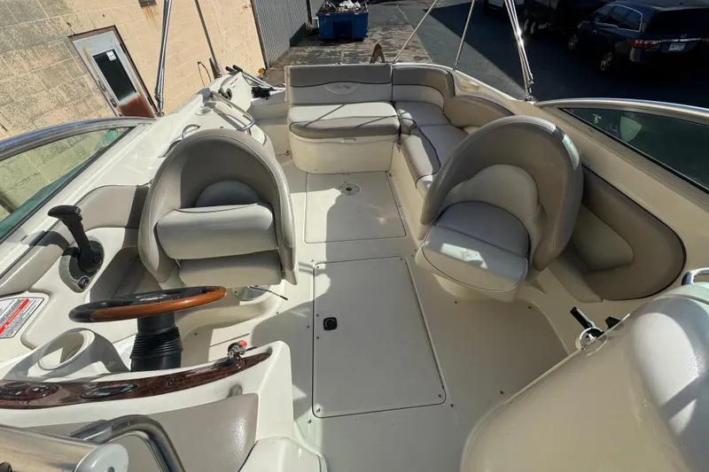 Slide: The Image of 2005 Sea Ray 240 Sundeck interior with seating and steering wheel, docked outdoors. - 24