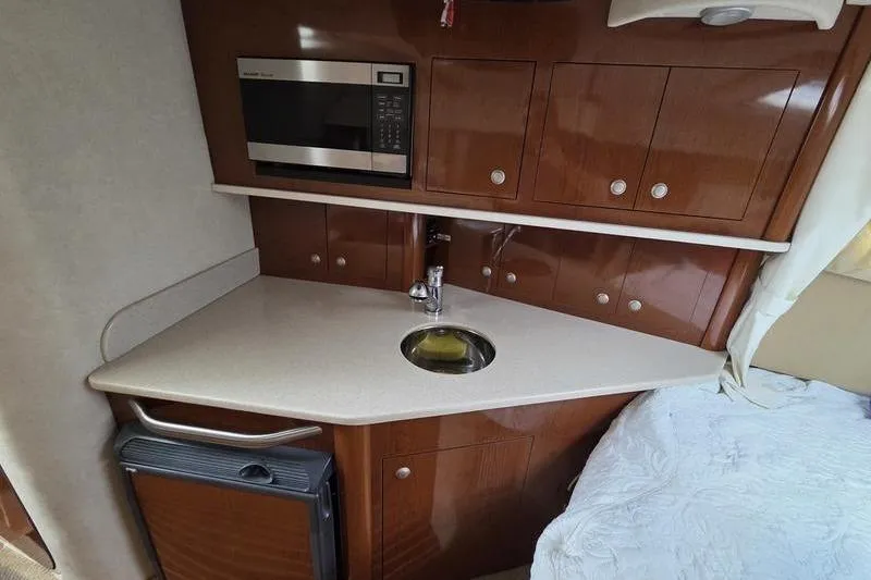 Slide: The Image of 2008 Sea Ray 290 Amberjack cabin kitchen with microwave, sink, and storage cabinets. - 15