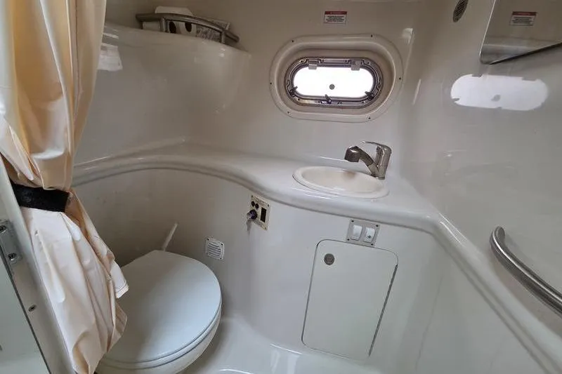 Slide: The Image of 2008 Sea Ray 290 Amberjack boat bathroom with toilet, sink, and porthole window. - 25