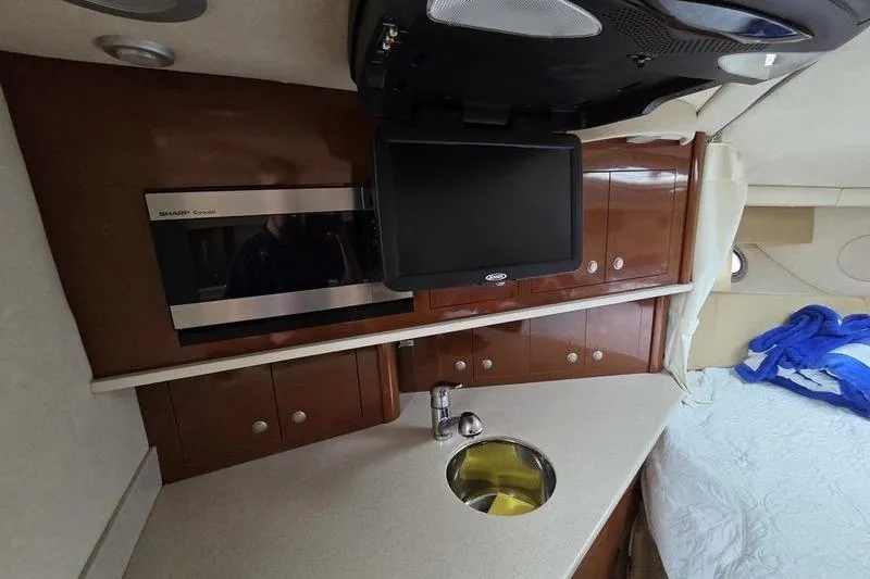 Slide: The Image of 2008 Sea Ray 290 Amberjack cabin interior with kitchenette, sink, and TV. - 26