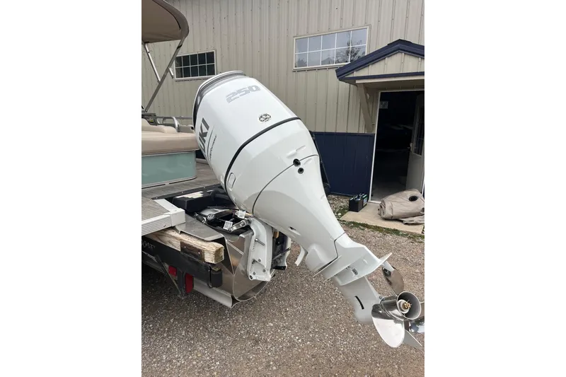 Slide: The Image of 2026 Tahoe 25 LTZ Entertainer boat with powerful outboard motor in a yard setting. - 11