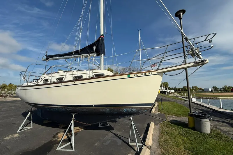 The Image of 1988 Island Packet 27 sailboat on stands, dockside, under clear blue sky. - 0