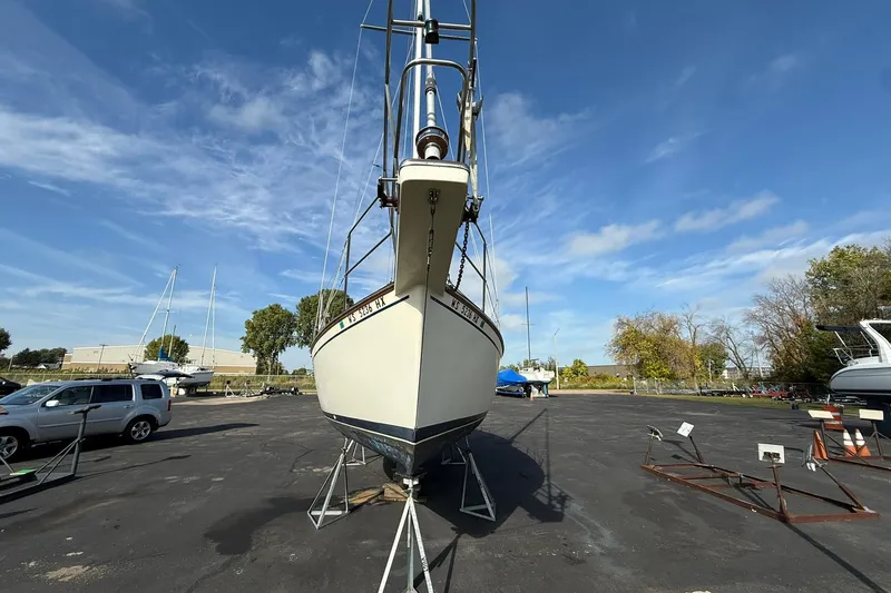 Slide: The Image of 1988 Island Packet 27 sailboat on stands in a parking lot under a clear blue sky. - 2