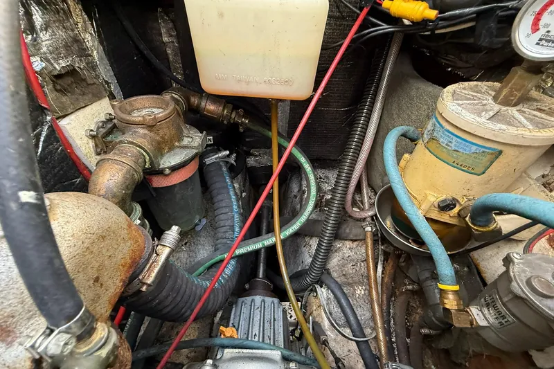 Slide: The Image of Engine compartment of a 1988 Island Packet 27 sailboat, showing hoses and mechanical components. - 23