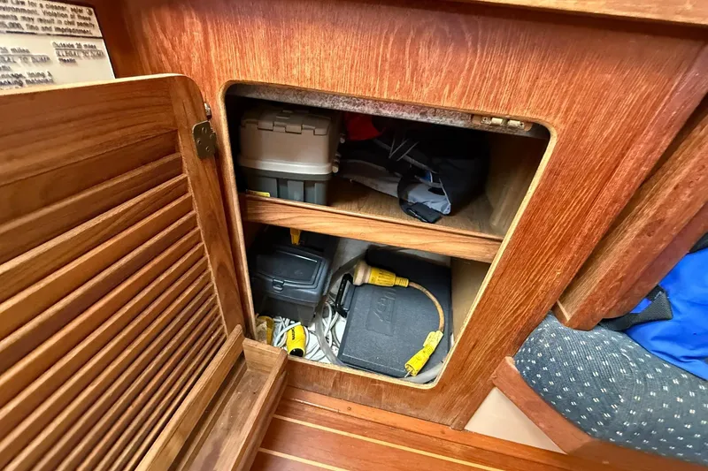 Slide: The Image of Wooden cabinet storage inside 1988 Island Packet 27 sailboat, containing tools and electrical cords. - 28
