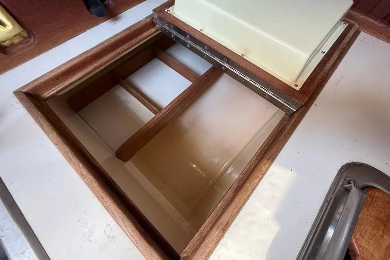 Slide: The Image of Open storage compartment on 1988 Island Packet 27 sailboat, featuring wooden trim and hinged lid. - 29