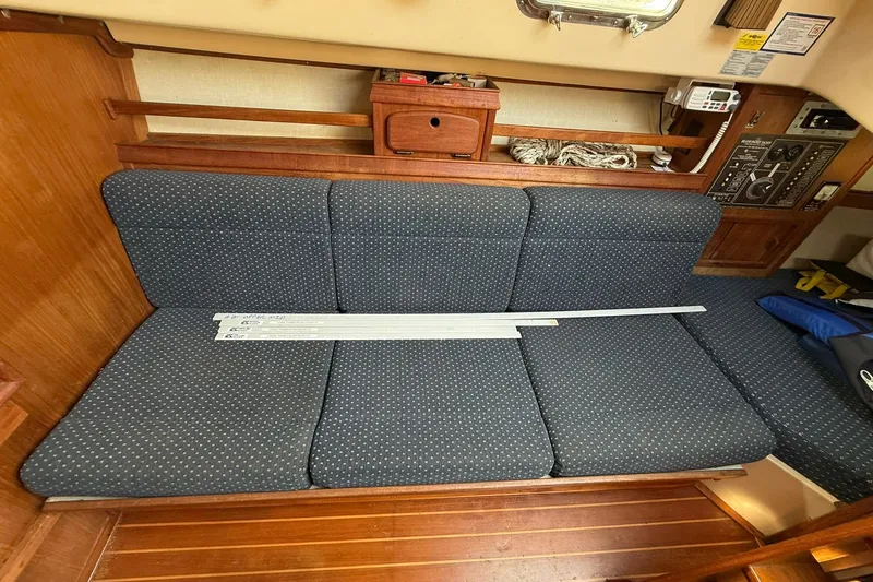 Slide: The Image of Interior of 1988 Island Packet 27 sailboat with blue cushioned seating and wooden accents. - 32