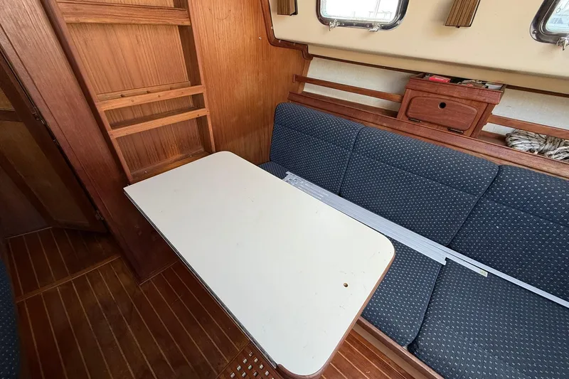 Slide: The Image of 1988 Island Packet 27 interior with wooden shelves, cushioned seating, and a white table. - 34