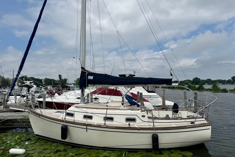 Slide: The Image of 1988 Island Packet 27 sailboat docked at a marina, surrounded by water lilies. - 1