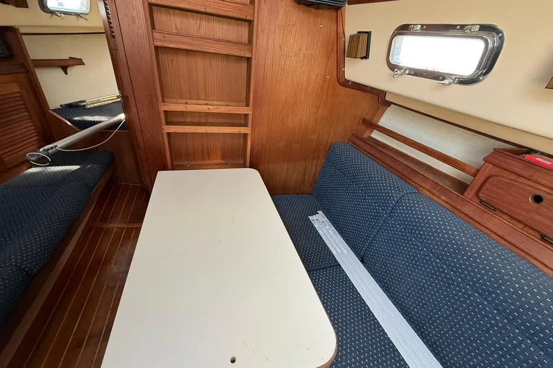 Slide: The Image of Interior of 1988 Island Packet 27 sailboat with wooden finish and blue seating. - 35