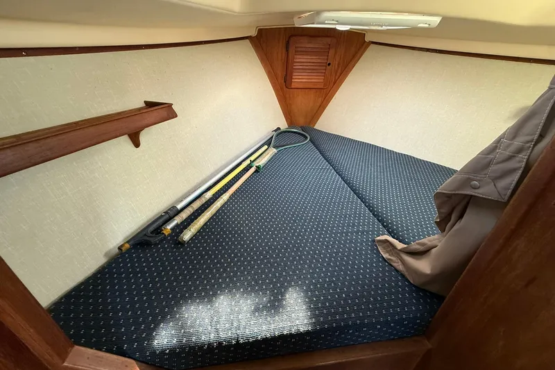 Slide: The Image of Cozy cabin interior of 1988 Island Packet 27 sailboat with fishing rods and storage. - 36