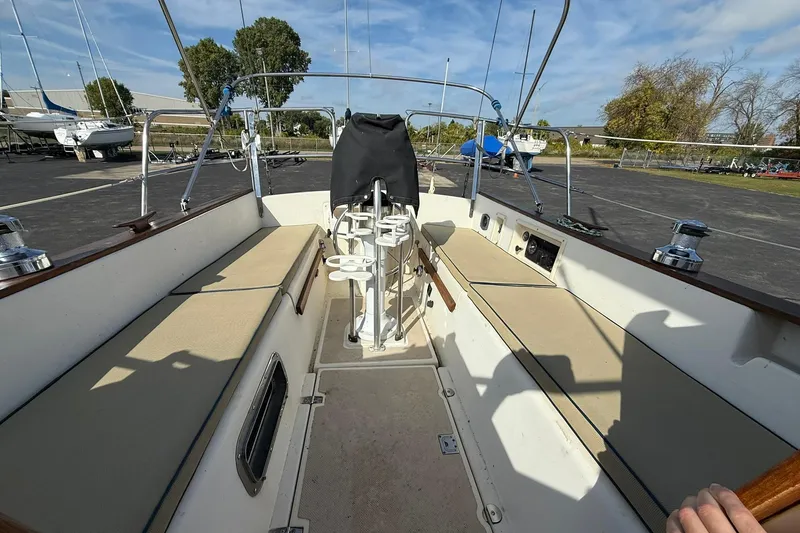 Slide: The Image of 1988 Island Packet 27 sailboat cockpit with seating, steering wheel, and winches under a clear sky. - 38