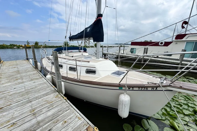 Slide: The Image of 1988 Island Packet 27 sailboat docked by a wooden pier on a calm lake. - 5