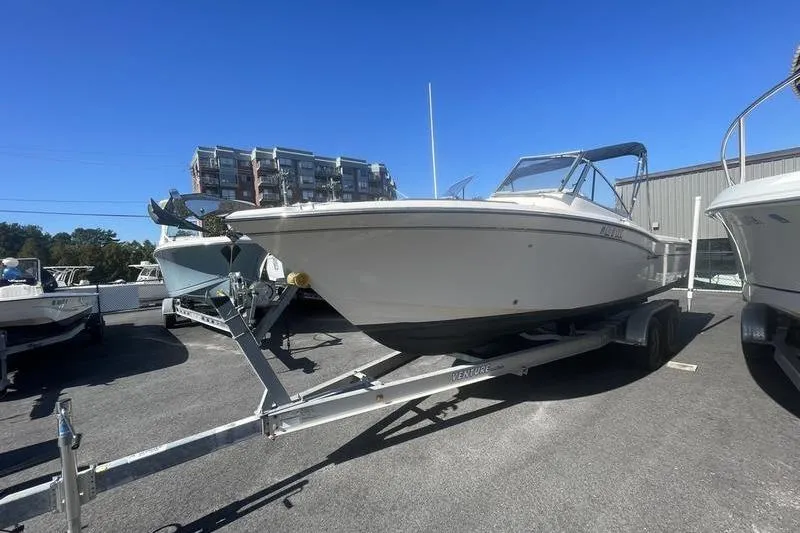 Slide: The Image of 2012 Grady-White Freedom 255 boat on trailer, parked outdoors under clear blue sky. - 4