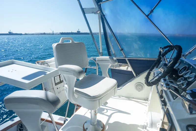Slide: The Image of 1984 Bertram 35 Convertible yacht helm with ocean view, featuring captain's chair and steering wheel. - 13