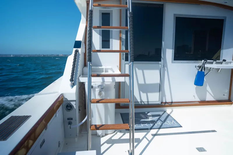 Slide: The Image of 1984 Bertram 35 Convertible yacht deck with ladder, ocean view, and clear blue sky. - 7