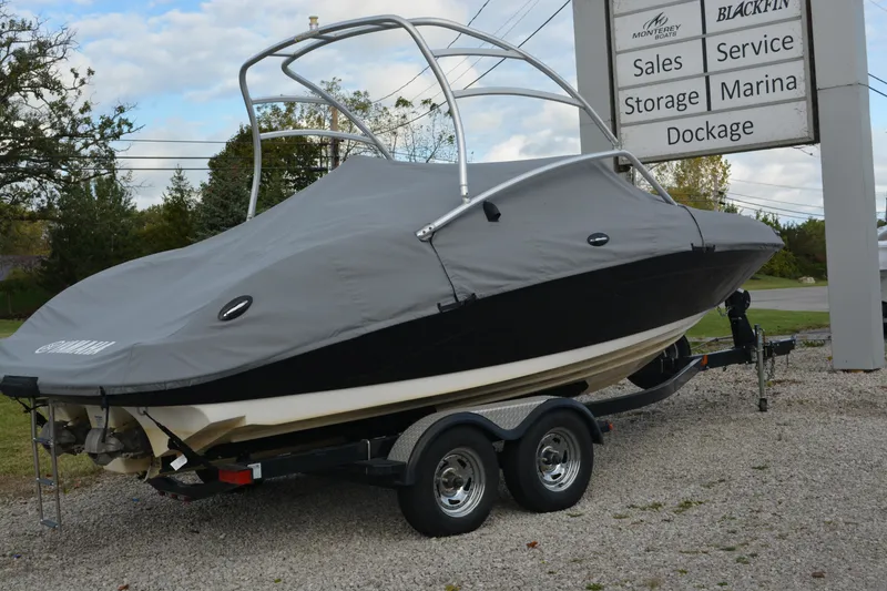 Slide: The Image of 2011 Yamaha AR210 boat covered on trailer near marina services sign. - 6