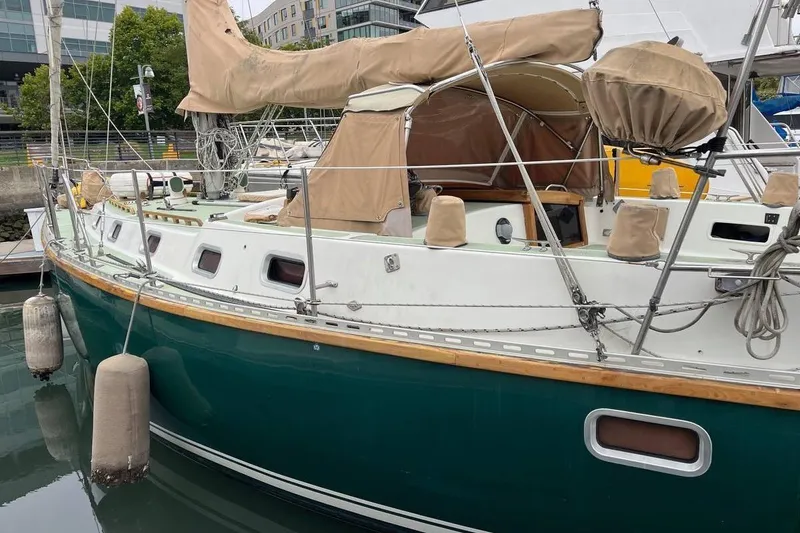 Slide: The Image of 1989 Fortuna 37 sailboat docked, featuring green hull and beige covers. - 3