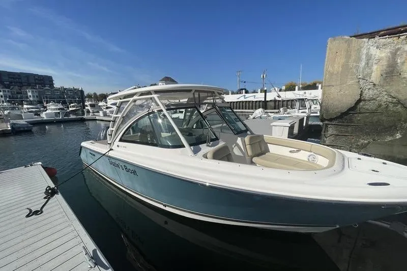 The Image of 2016 Pursuit DC 265 Dual Console boat docked in a marina under clear blue skies. - 1