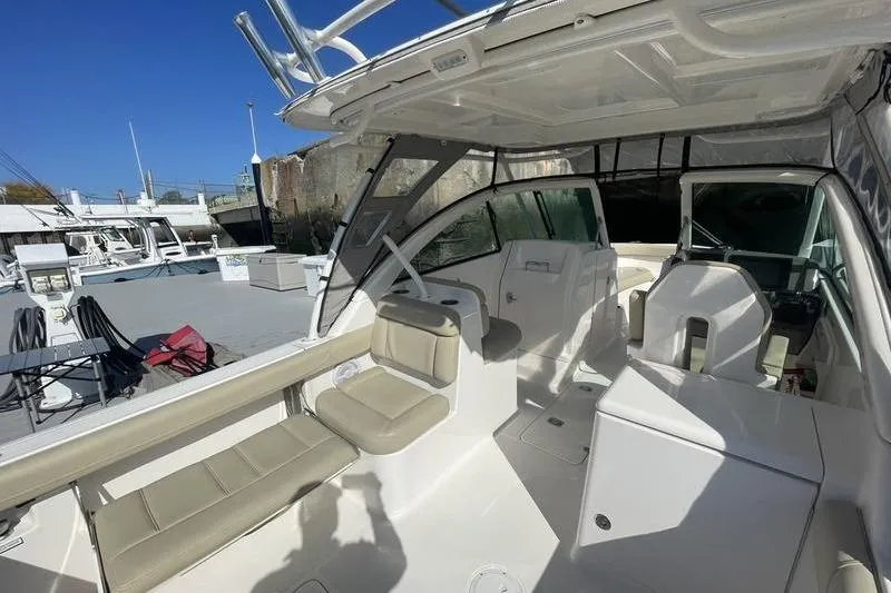 Slide: The Image of 2016 Pursuit DC 265 Dual Console boat interior with seating and helm, docked under clear sky. - 10