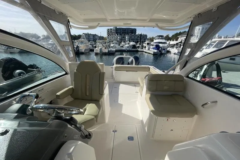 Slide: The Image of 2016 Pursuit DC 265 Dual Console boat interior at marina, showcasing seating and helm. - 12