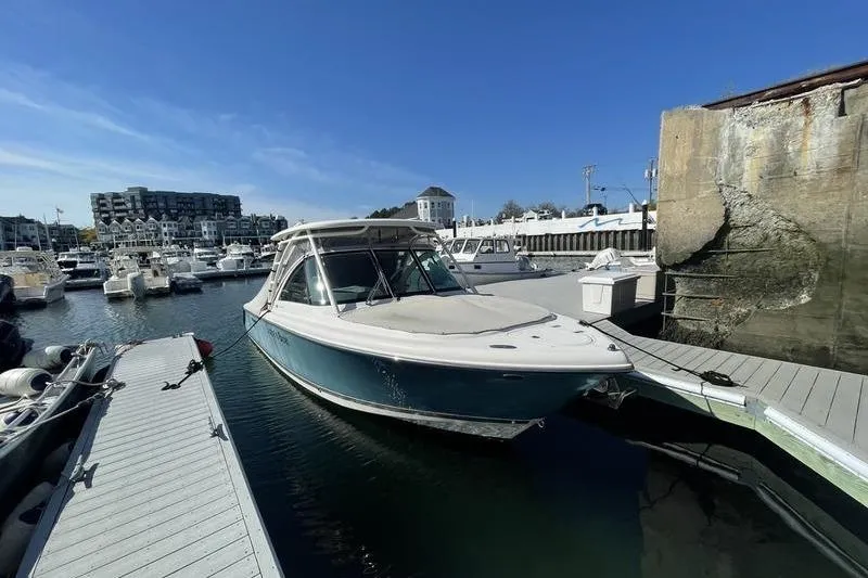 Slide: The Image of 2016 Pursuit DC 265 Dual Console boat docked in a marina under clear blue skies. - 4
