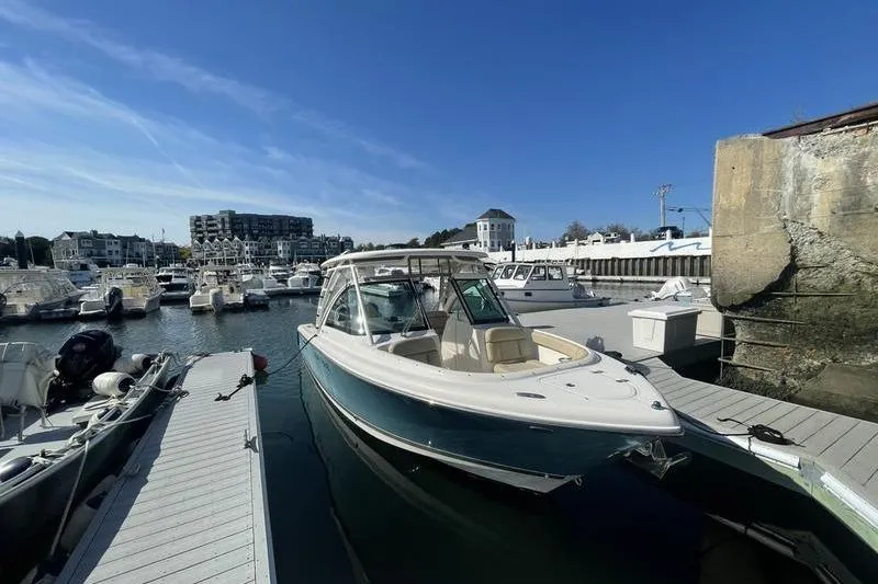 Slide: The Image of 2016 Pursuit DC 265 Dual Console boat docked in a marina under clear blue skies. - 6