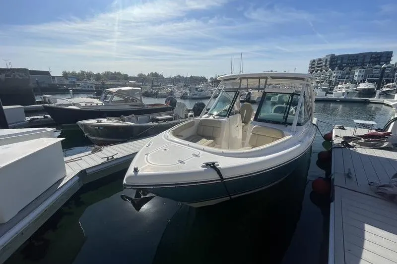 Slide: The Image of 2016 Pursuit DC 265 Dual Console boat docked in a marina under clear skies. - 9