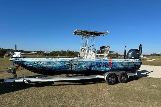 The Image of 2023 Skeeter SX240 boat on trailer, vibrant graphics, clear blue sky background. - 0