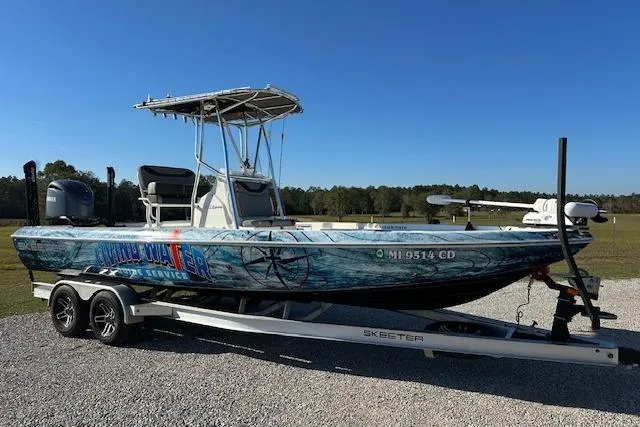 Slide: The Image of 2023 Skeeter SX240 boat on trailer, parked outdoors under clear blue sky. - 4