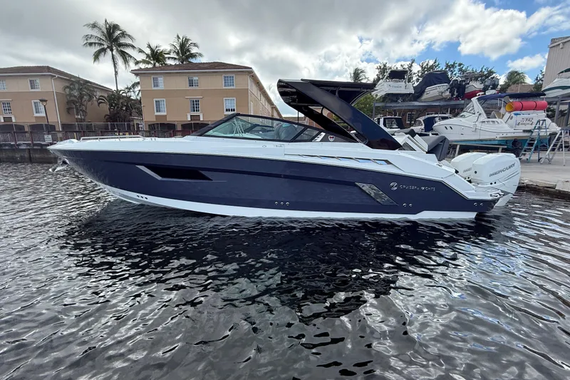 The Image of 2019 Cruisers Yachts 338 Outboard on water, with palm trees and buildings in background. - 0