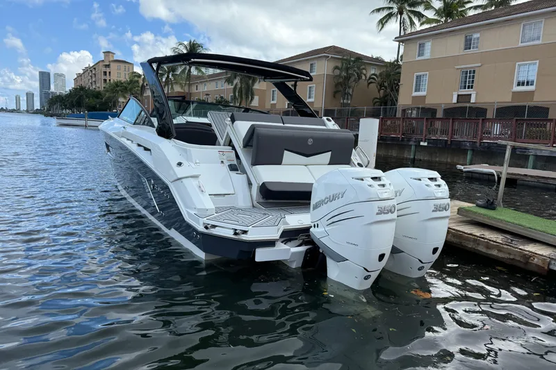 Slide: The Image of 2019 Cruisers Yachts 338 Outboard with twin Mercury engines docked by waterfront homes. - 2