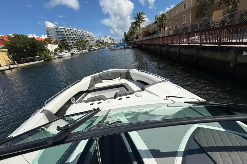 Slide: The Image of 2019 Cruisers Yachts 338 Outboard navigating a scenic canal with modern buildings. - 22