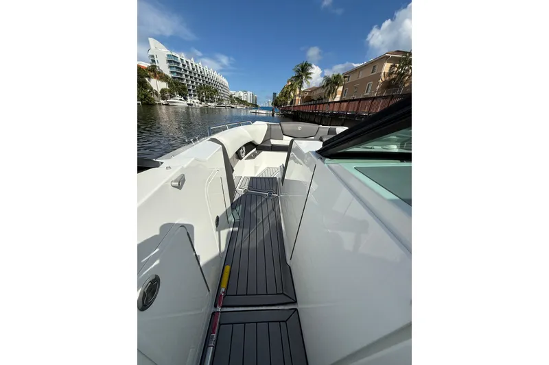 Slide: The Image of 2019 Cruisers Yachts 338 Outboard, sleek deck view, docked near waterfront buildings. - 26