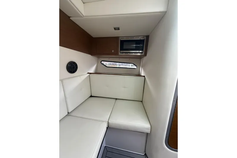 Slide: The Image of 2019 Cruisers Yachts 338 Outboard cabin interior with white seating and microwave. - 36