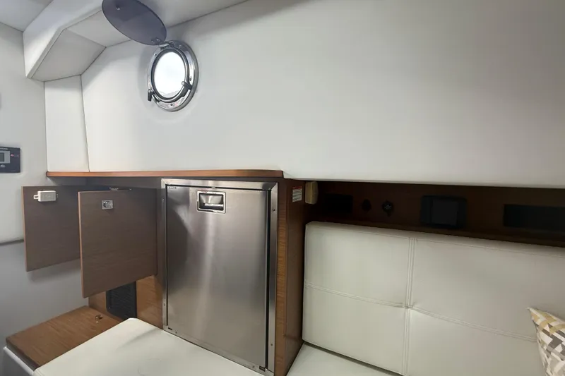 Slide: The Image of Interior of 2019 Cruisers Yachts 338 Outboard, featuring a compact cabin with porthole. - 38