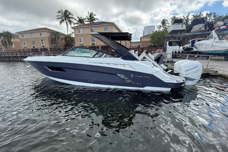 Slide: The Image of 2019 Cruisers Yachts 338 Outboard in marina, sleek design, palm trees in background. - 4