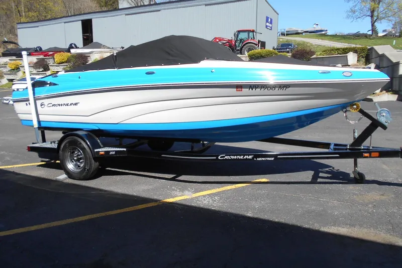 Slide: The Image of 2019 Crownline 205 SS boat on trailer, blue and white design, parked outdoors. - 14