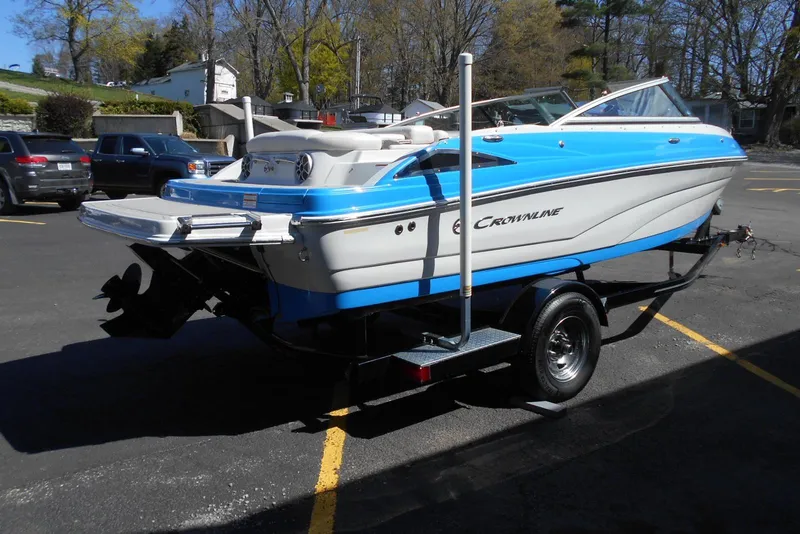 Slide: The Image of 2019 Crownline 205 SS boat on trailer, blue and white design, parked outdoors. - 4