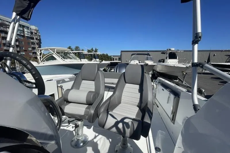 Slide: The Image of 2022 Jeanneau 7.5 Leader boat with dual gray seats, docked under clear blue sky. - 13