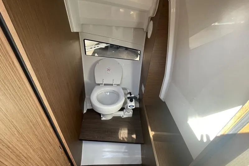 Slide: The Image of 2022 Jeanneau 7.5 Leader boat bathroom with toilet and wooden accents. - 14