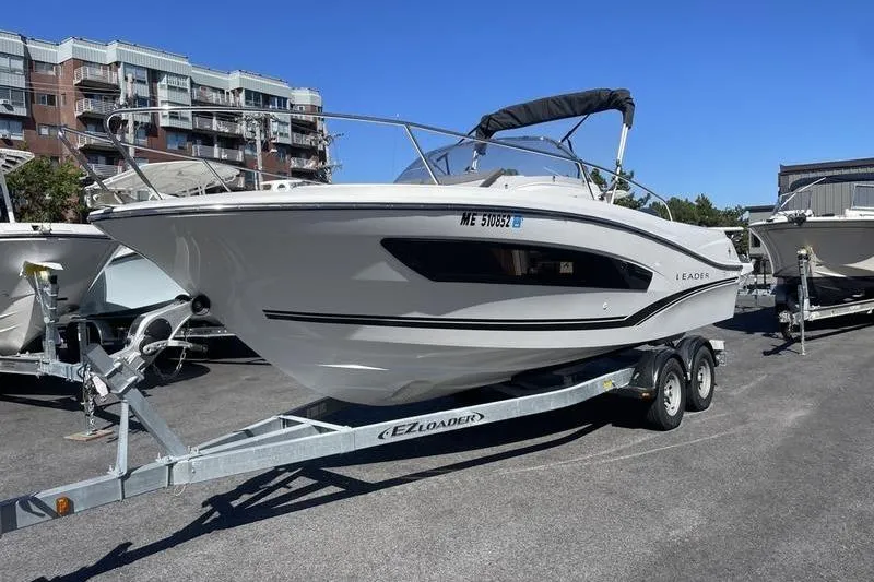 Slide: The Image of 2022 Jeanneau 7.5 Leader boat on trailer, parked in urban setting. - 6