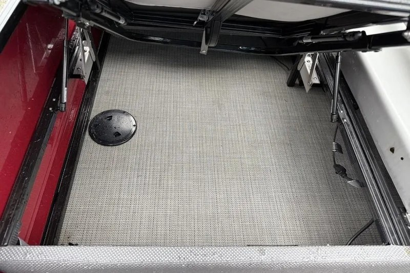 Slide: The Image of 2023 Regency 250 DL3 boat storage compartment with gray flooring and black hatch cover. - 20
